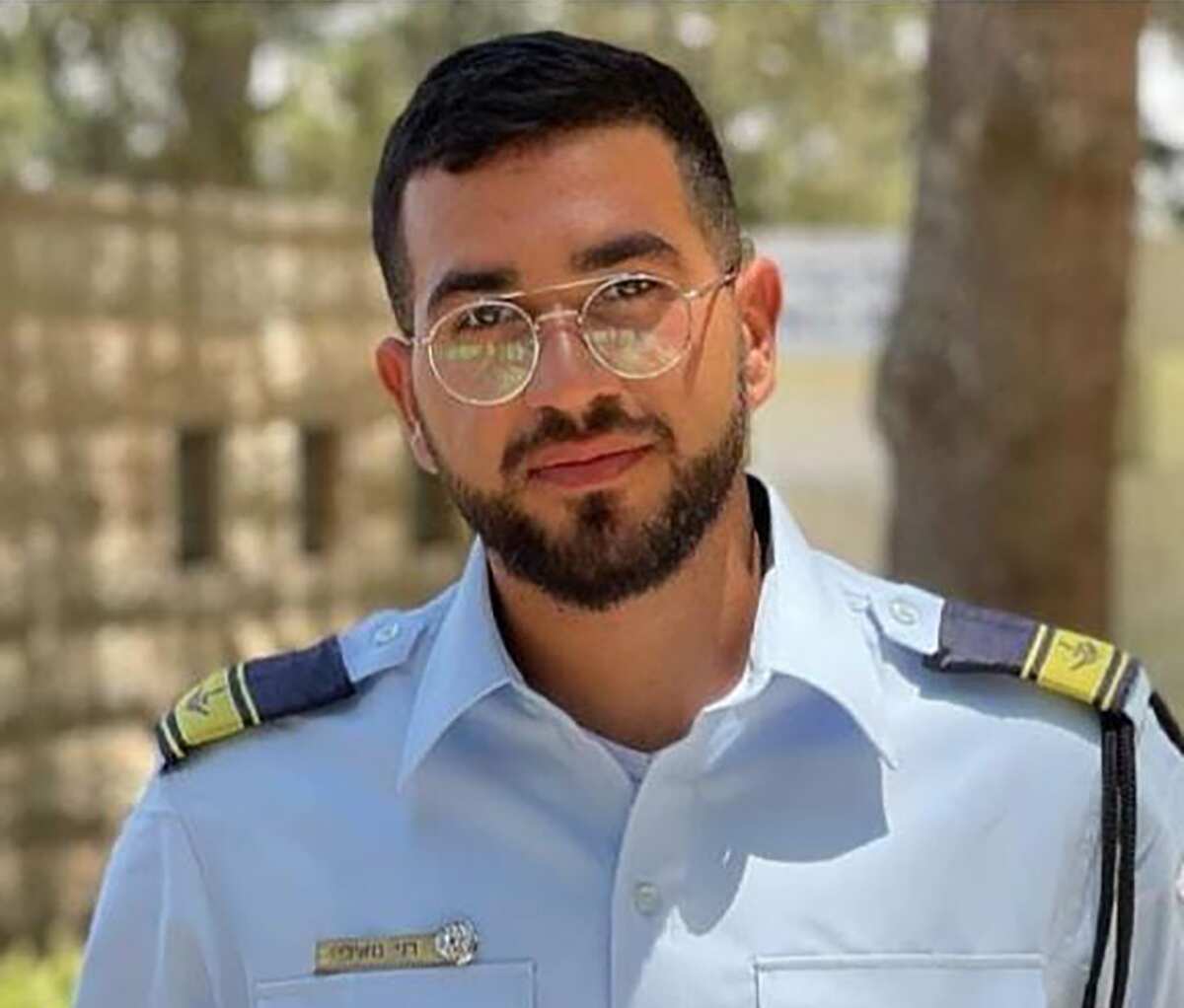 A young man with black hair and glasses wearing a blue uniform