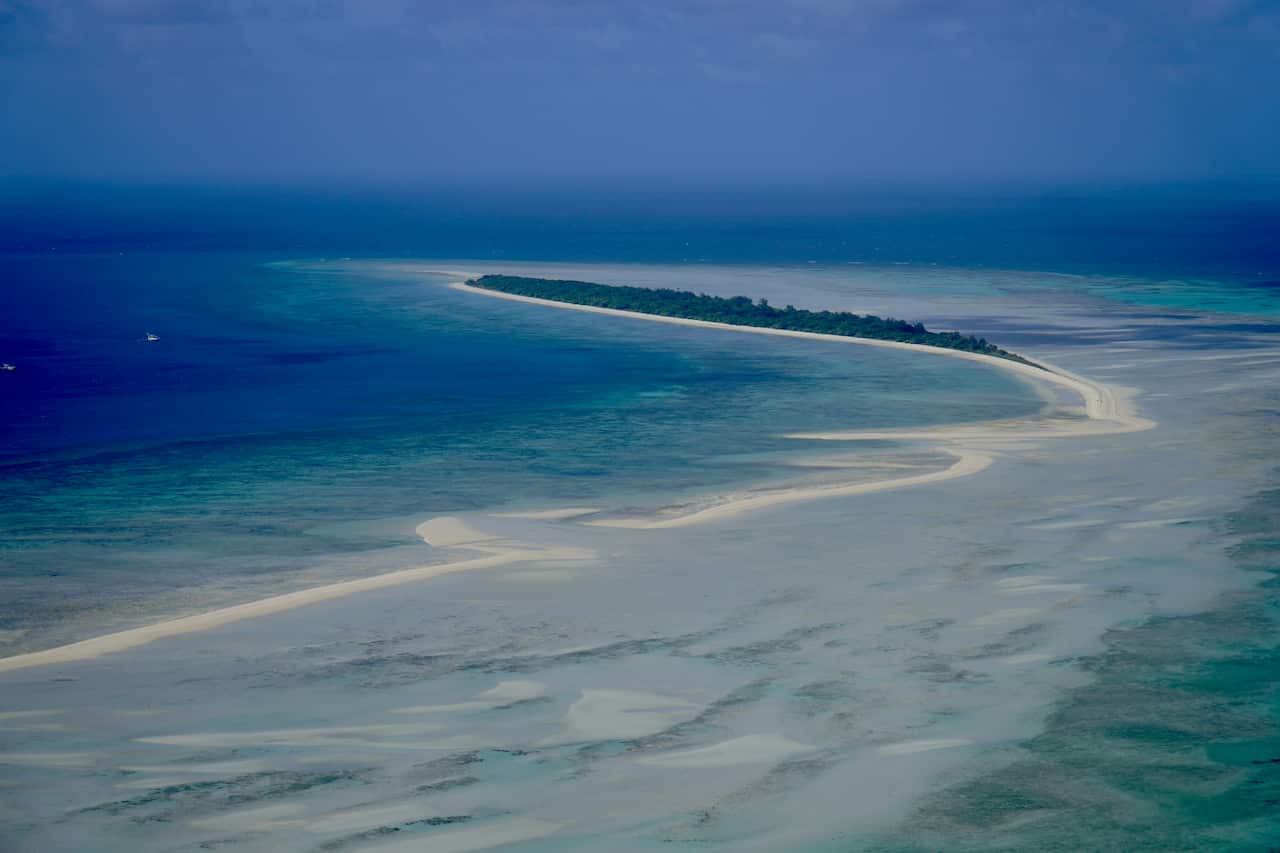 A drone shot of the tear-shaped Masig Island in the blue oceans of the Torres Strait.
