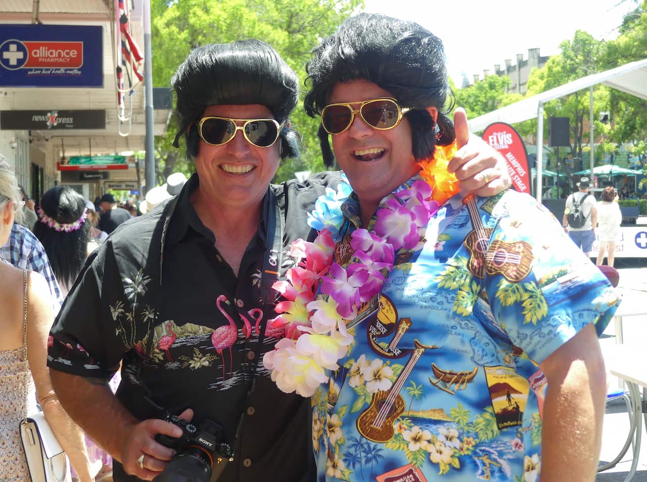Two men in Elvis wigs and bright Hawaiian shirts.