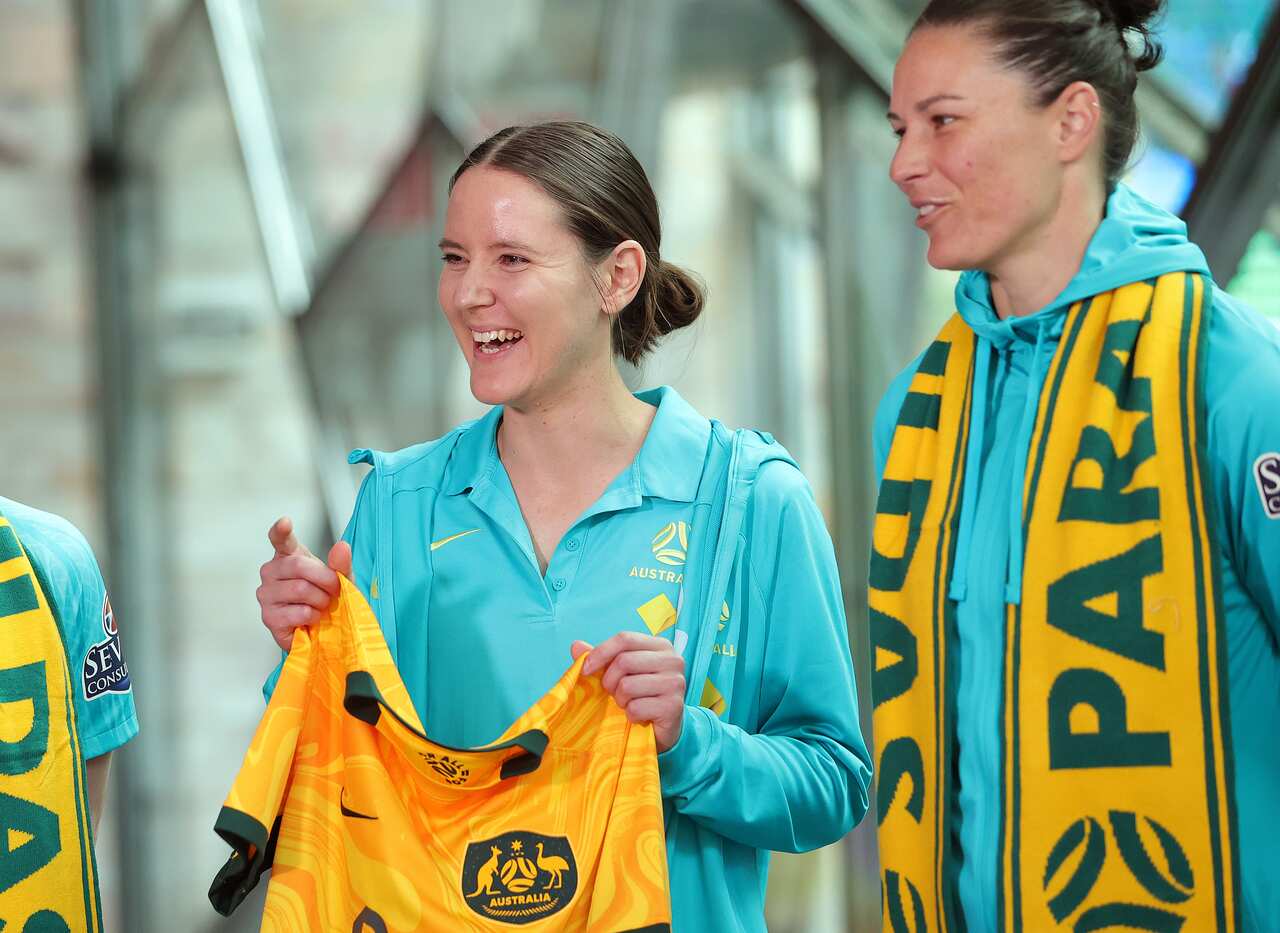 A woman smiles while holding a football jersey. 