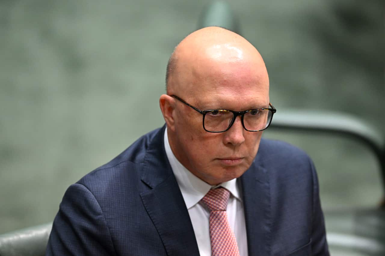 A man in a suit, wearing a tie and glasses, is frowning.