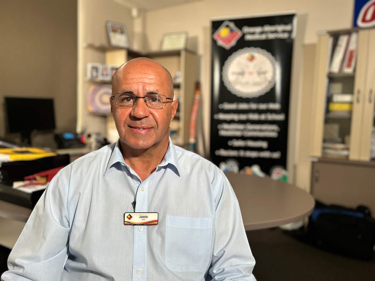 A man wearing a light blue business shirt sitting in an office 