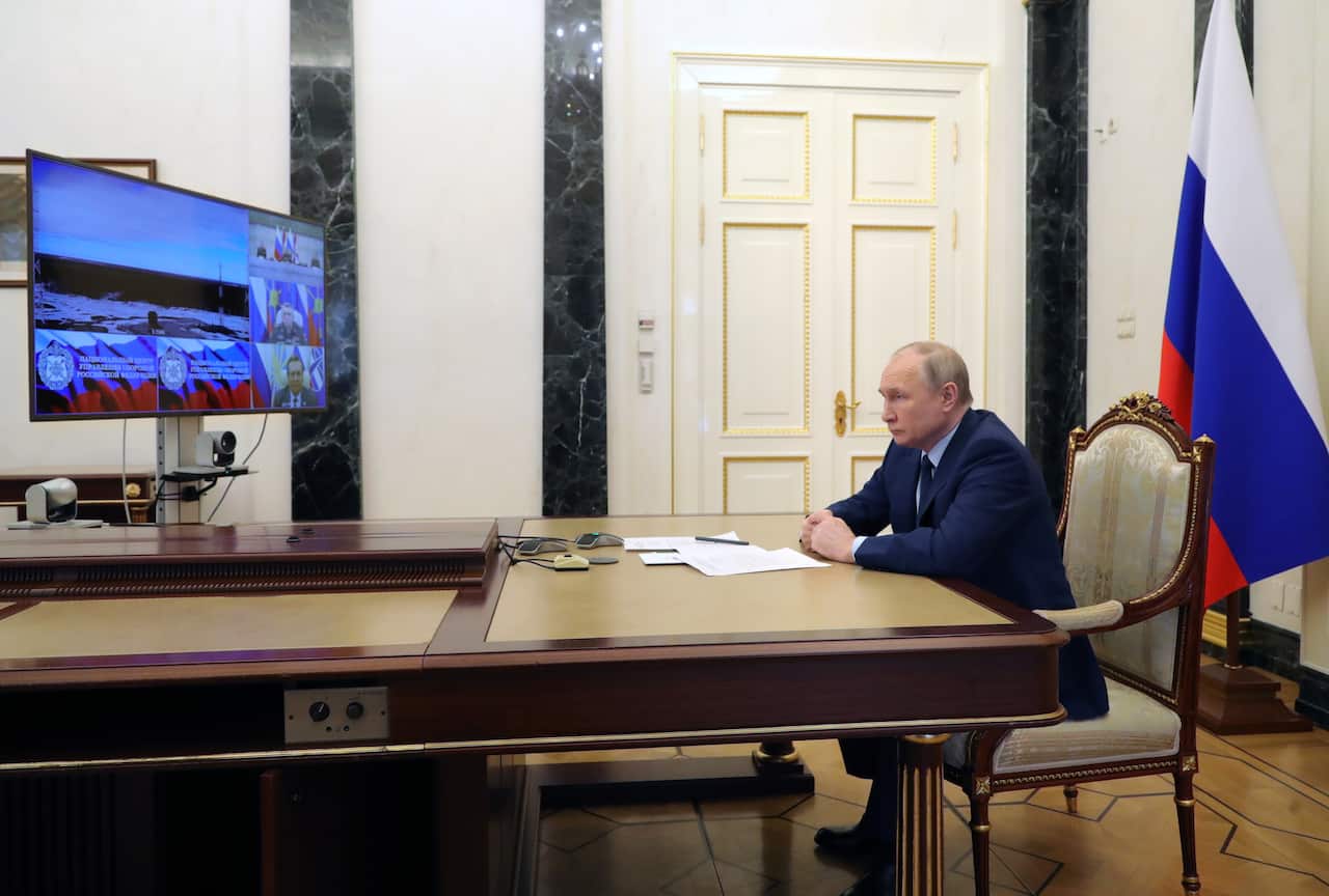 A man sitting at a desk watching a screen.