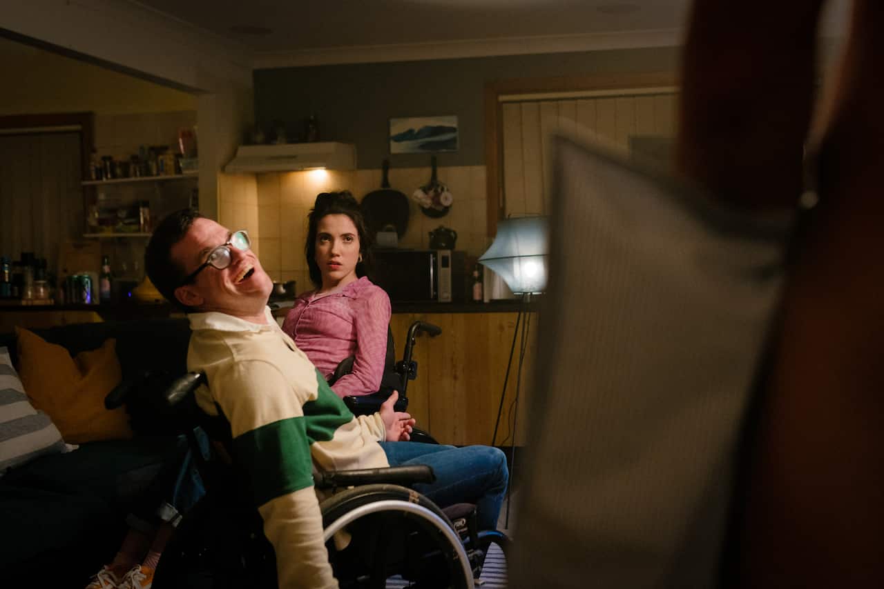Two people in wheelchairs are in a living room. 