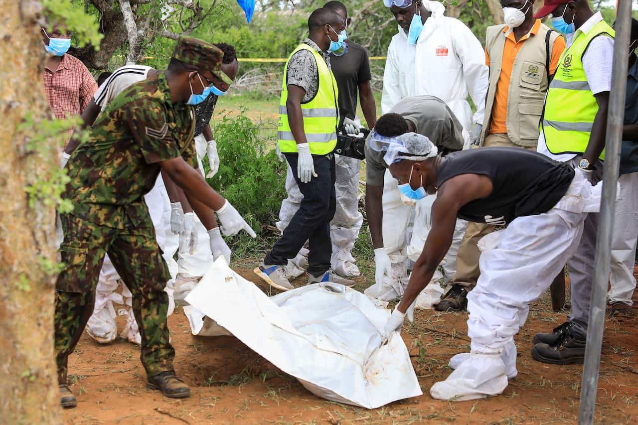 Homicide detectives and forensic experts exhume bodies from a mass grave.