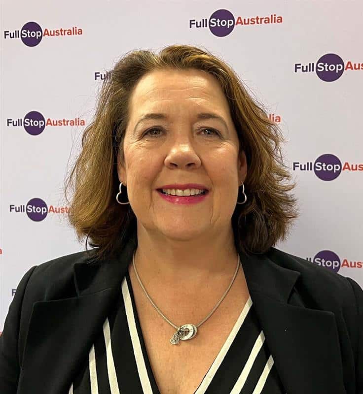 A woman standing in front of the Full Stop Australia logo.