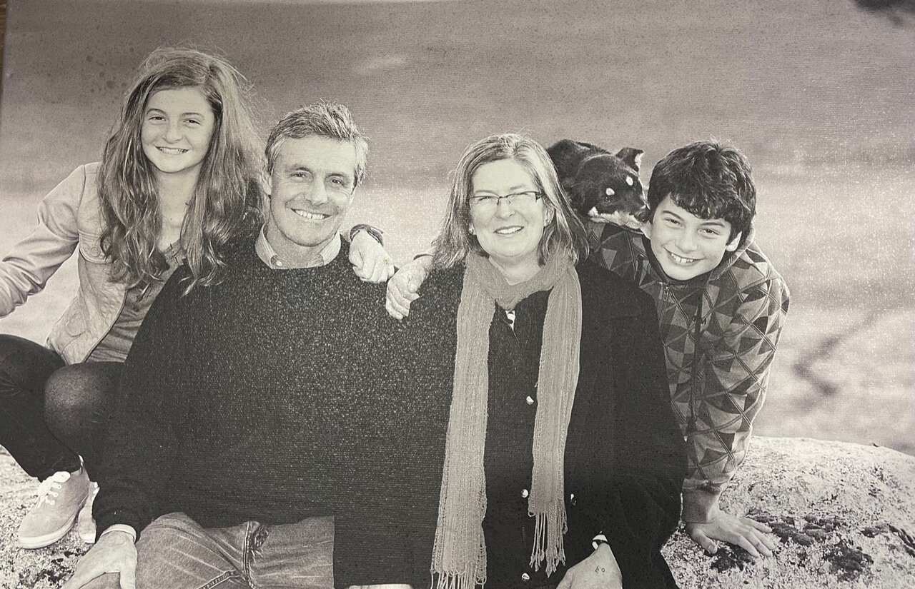 A black and white family photo of a mum, dad, son and daughter, all smiling for the camera.