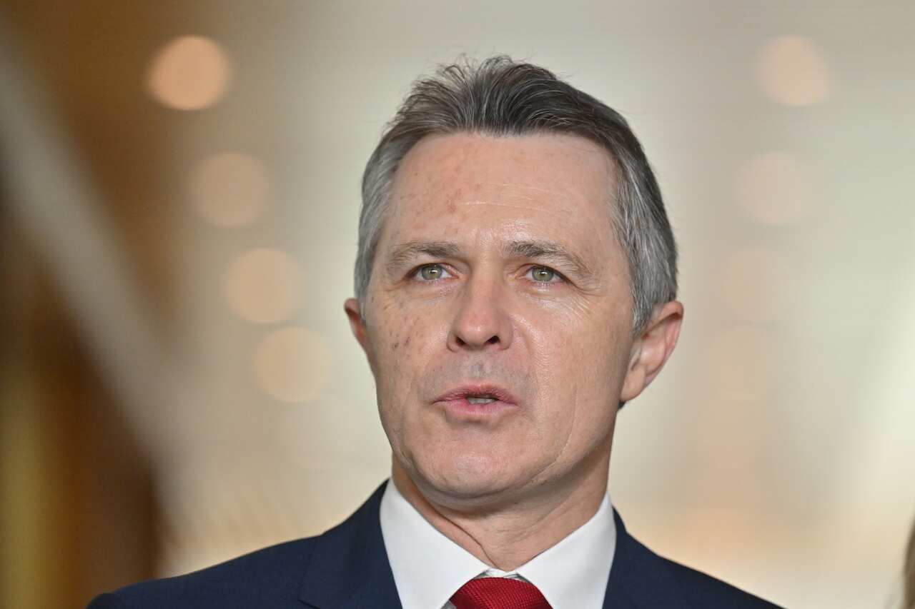 A man with silver hair in a dark suit with a red tie 