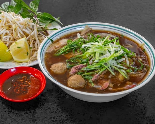 bowl of noodle soup (pho) with condiments