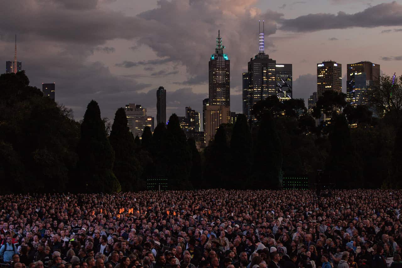 A huge crowd of people with a city skyline in the background.