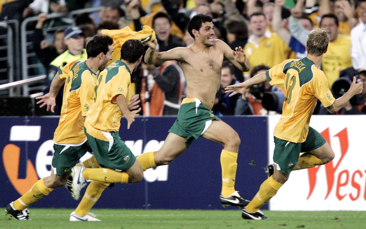 A shirtless footballer in green shorts runs amid other players wearing yellow jerseys and green shorts 