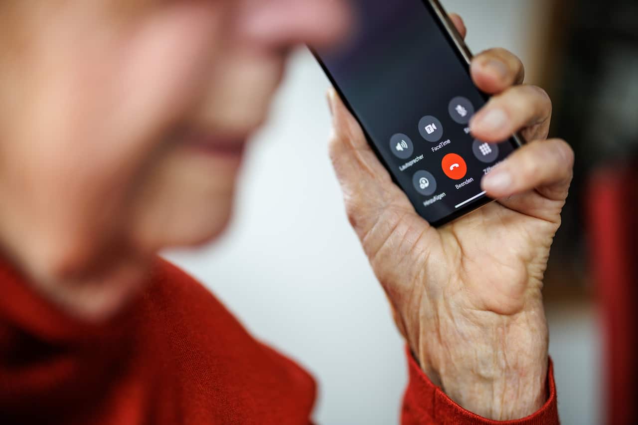 An older woman holding a mobile phone up to her ear with her left hand