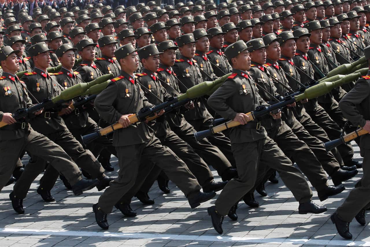 North Korean soldiers are marching in formation while holding their rifles.
