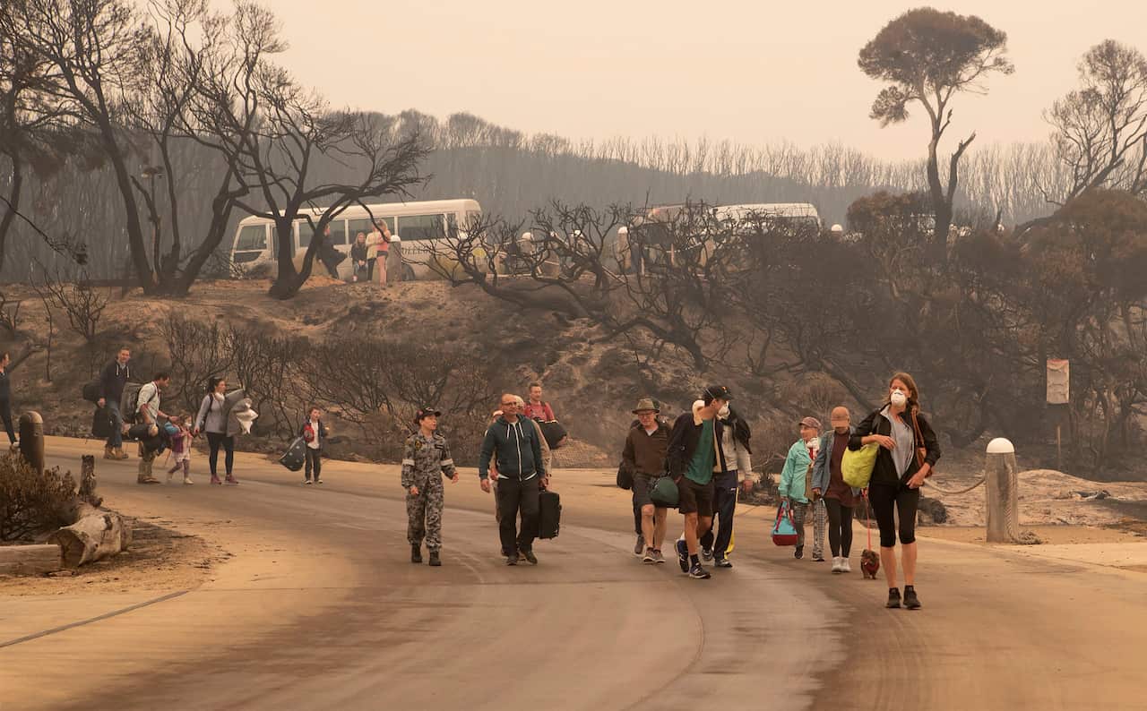 People carrying their belongings walking down a road.