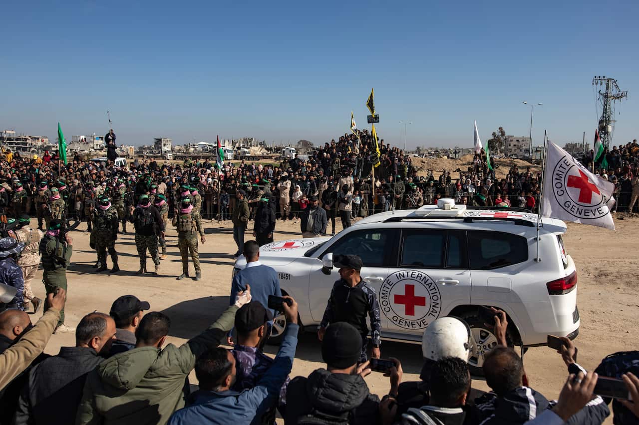 A crowd gathers around a Red Cross vehicle during the handover of Israeli hostages. 