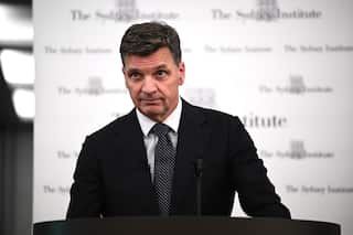 Angus Taylor speaking in Sydney behind a lecturn with a white background, wearing a polkadot tie