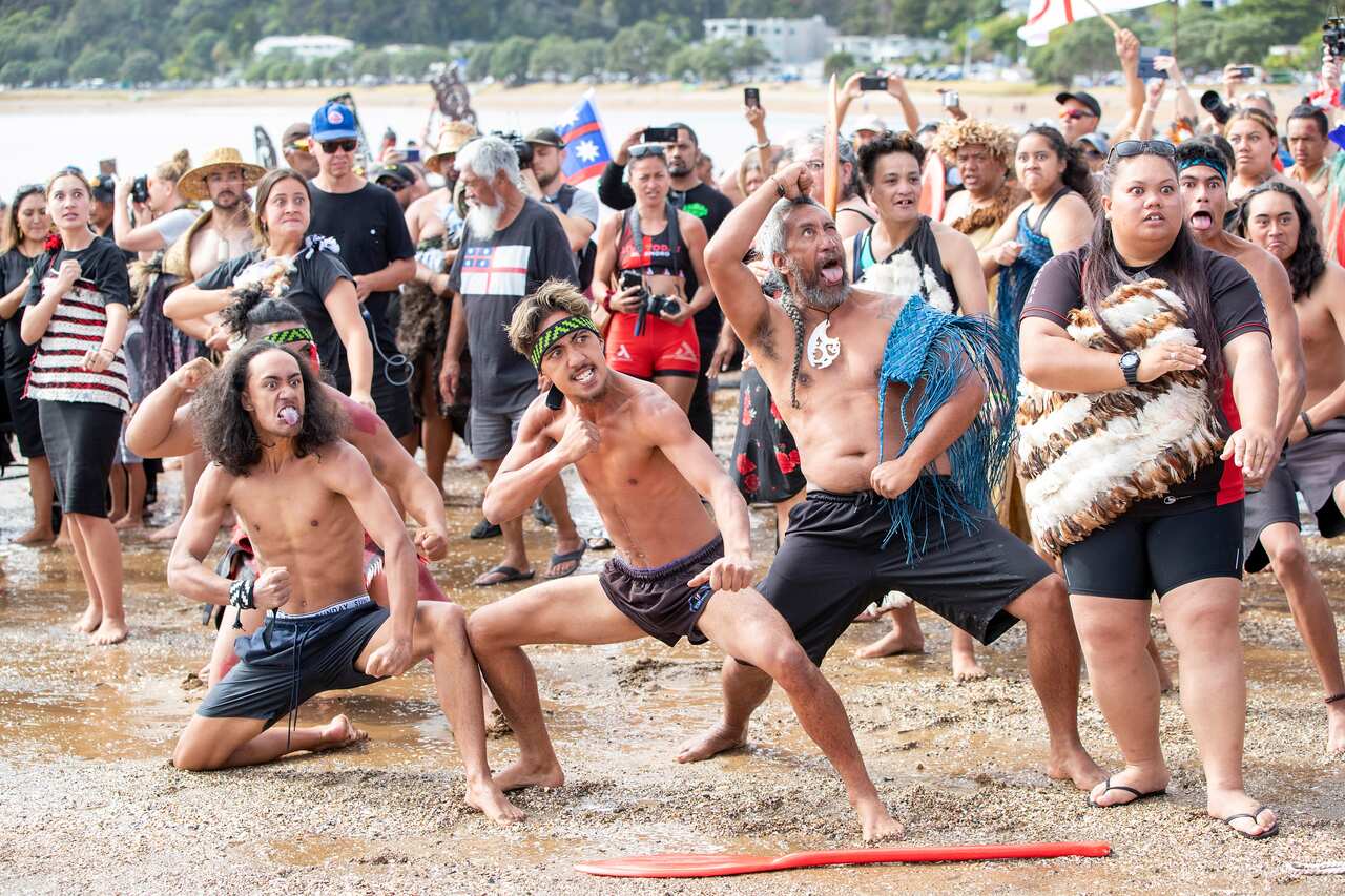 People perform a haka on a beach