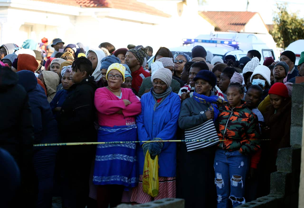 People stand behind a police cordon outside a nightclub in East London in South Africa where 21 people died. 