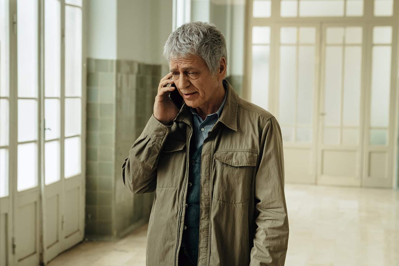 A man stands in a hallway, talking on a phone.