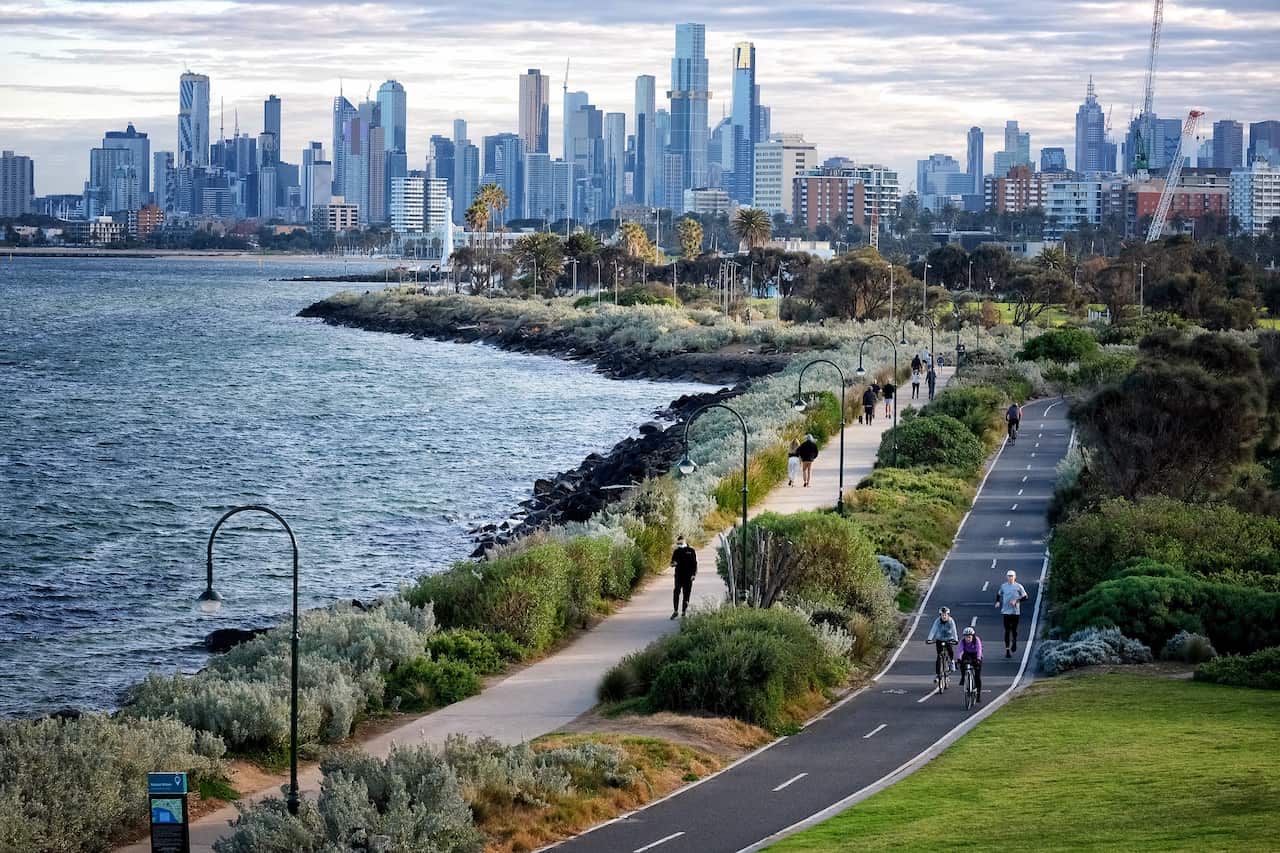 People walk, run and ride their bikes along a pathway at St Kilda in Melbourne.