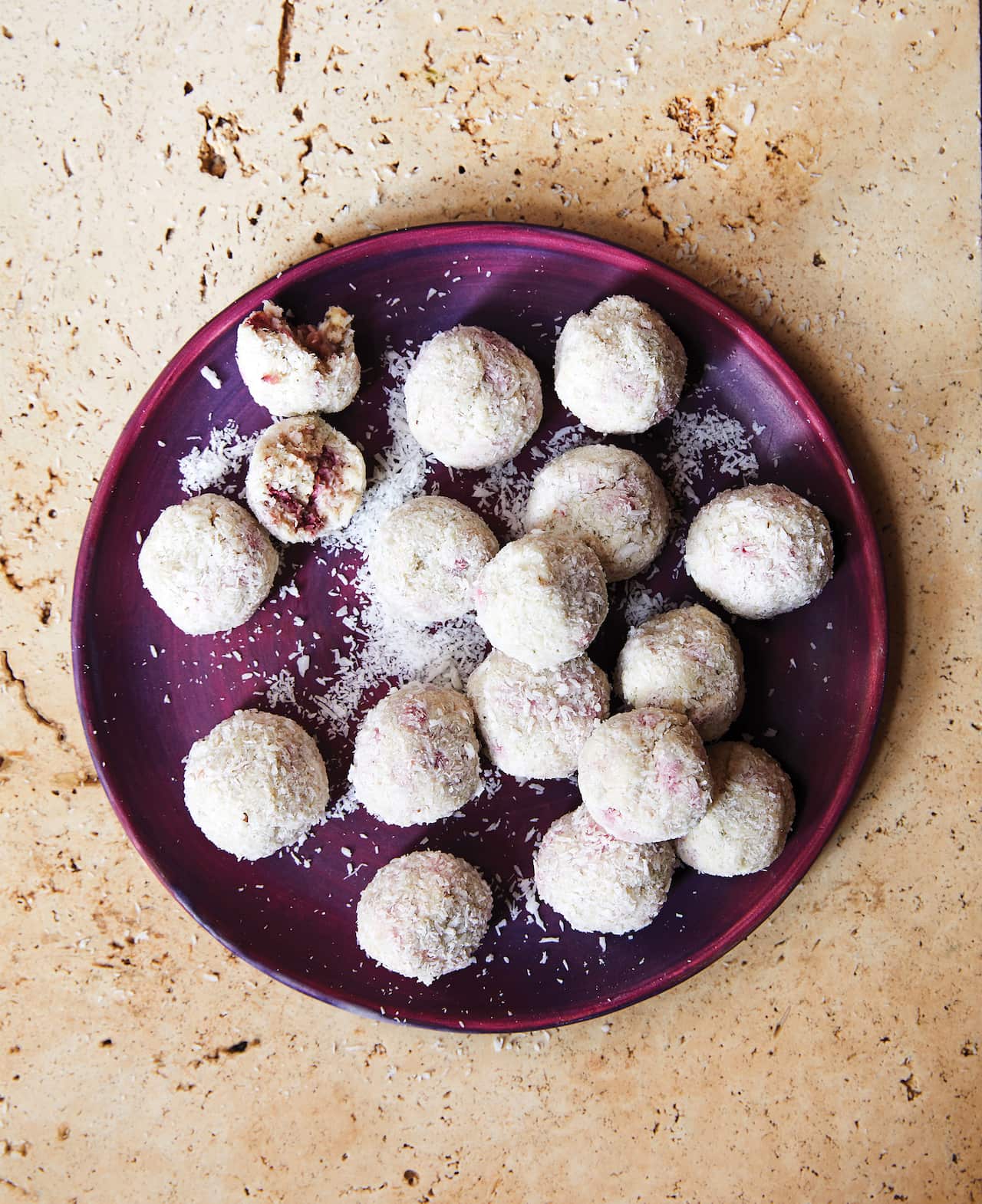 Pink-speckled strawgberry gum balls sit on a purple plate.
