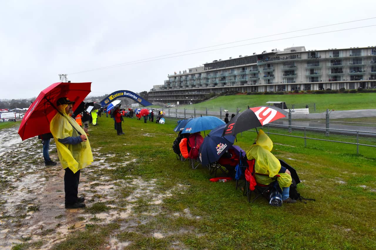 Bathurst 1000 spectators wearing ponchos and holding umbrellas.