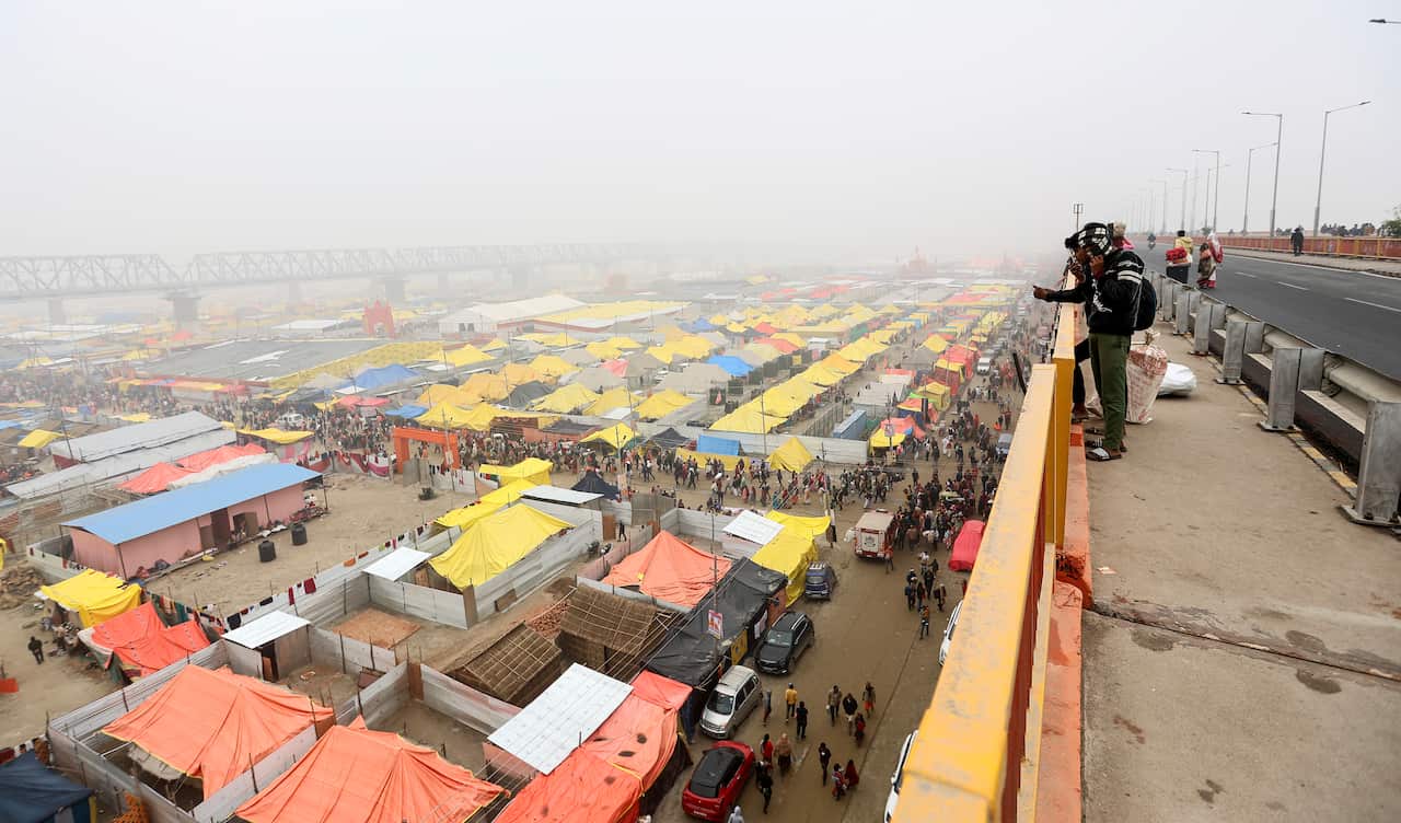 A view from above of yellow, blue and orange tents stretching off into the misty distance.