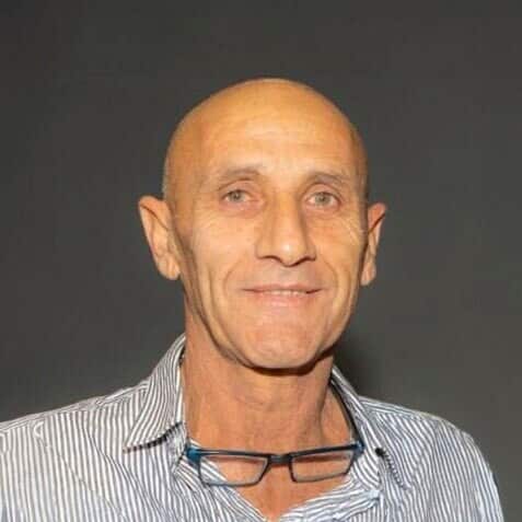 A man wearing a blue and white striped shirt, smiling.