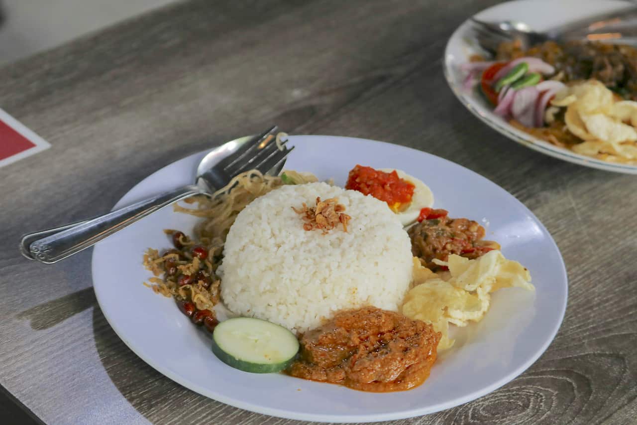 Nasi lemak, a traditional Malay curry paste rice dish served on a white plate. Photo aldrin-rachman-pradana-unsplash.jpeg