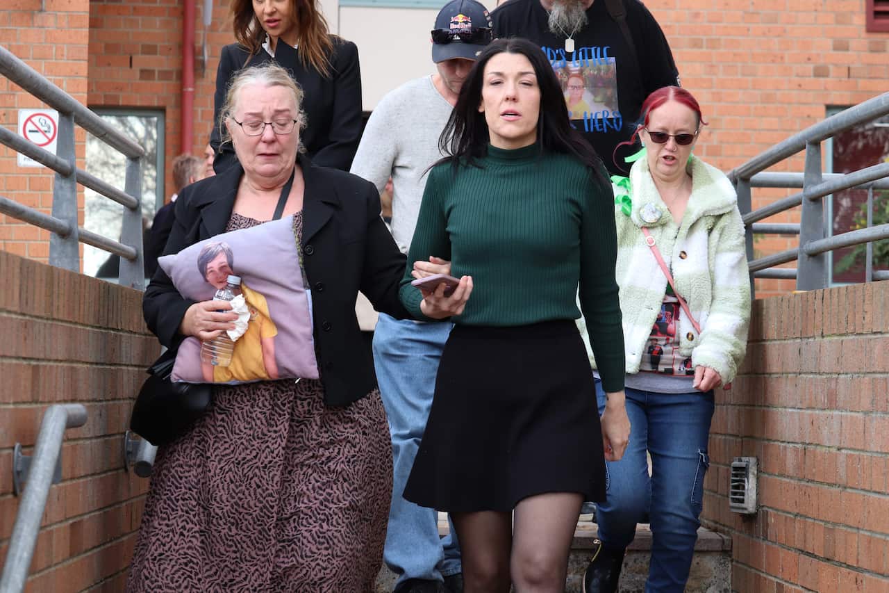 A group of people walking down stairs. Two are crying.