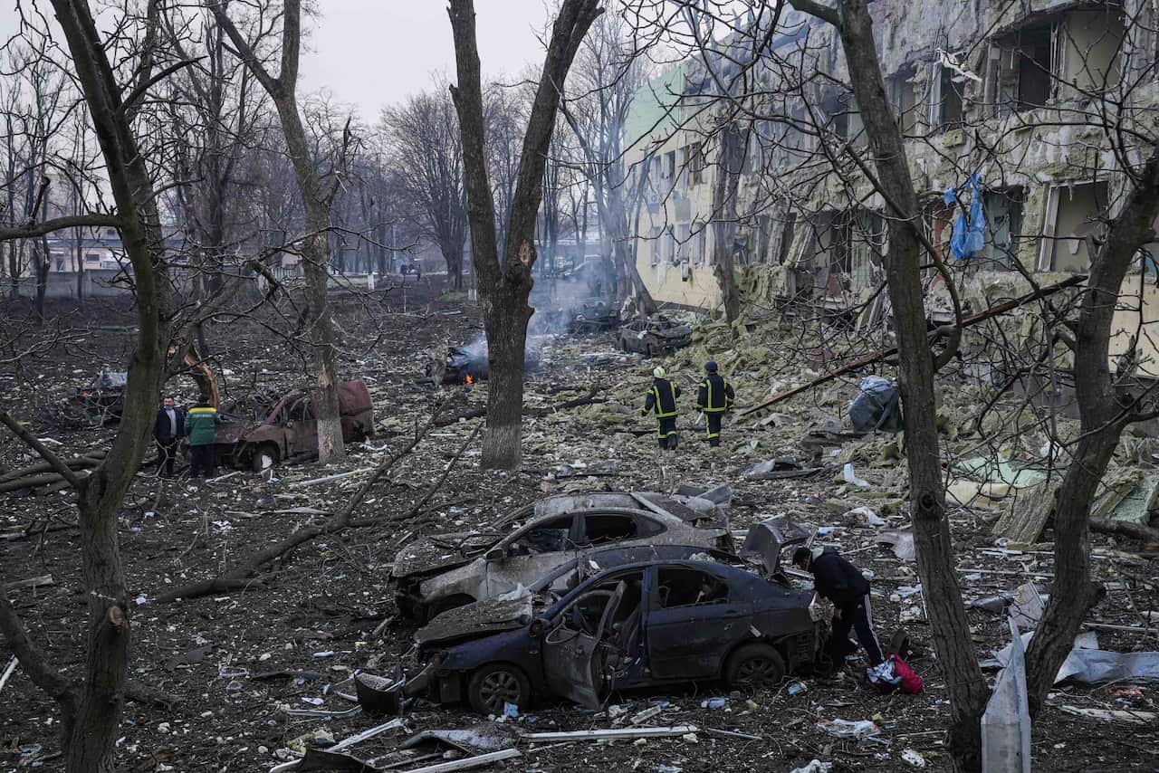 Ukrainian emergency employees are seen working at the side of a maternity hospital damaged by shelling.