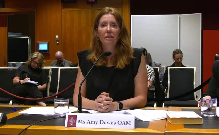 A woman wearing a black dress sits behind a microphone. 