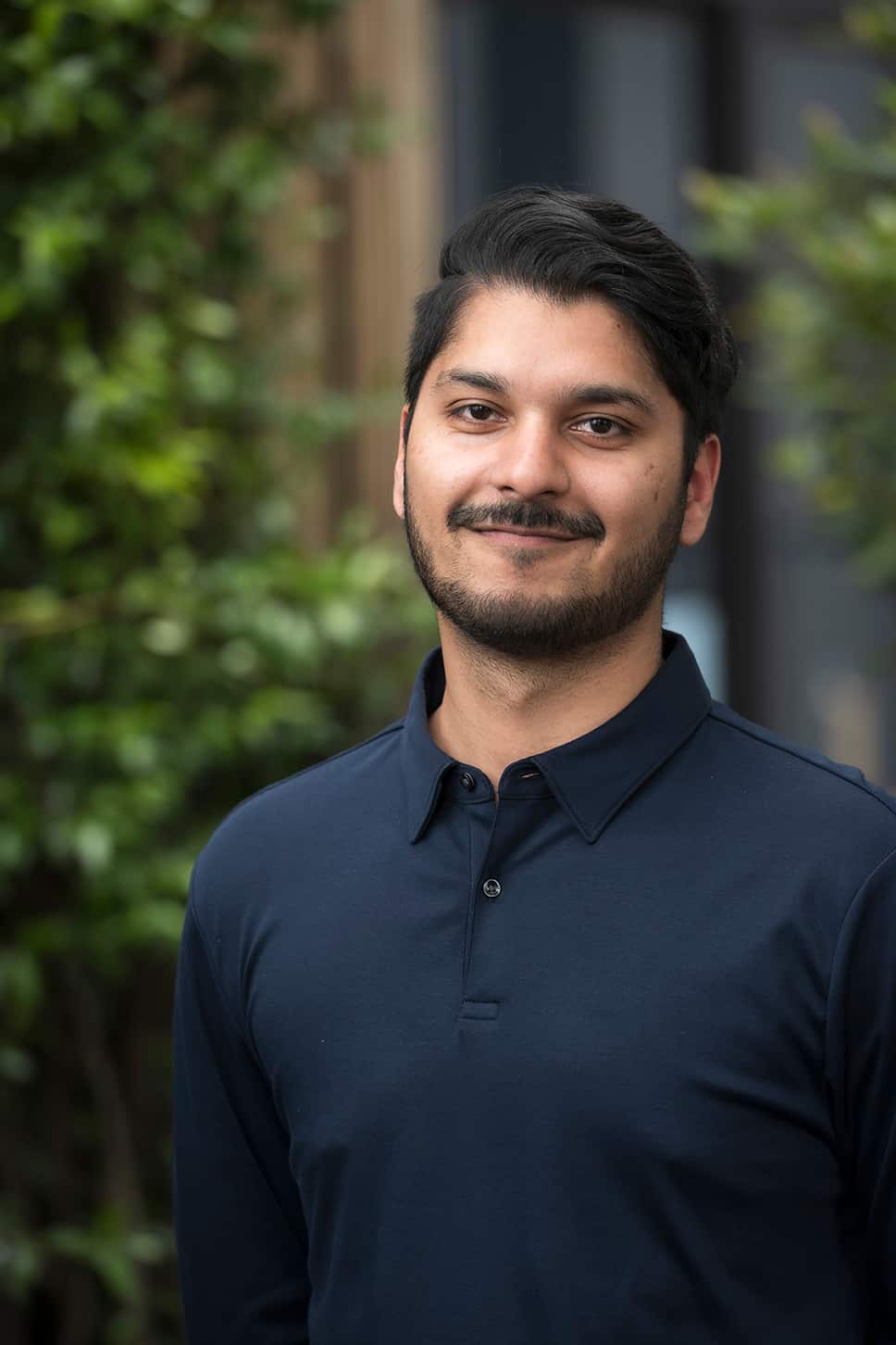 PhD Candidate Navyaan Siddiqui in a black shirt smiling at the camera