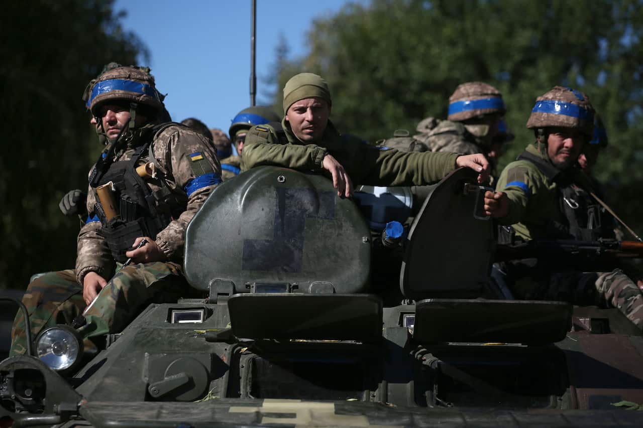 Ukrainian soldiers sit on an armoured personnel carrier.