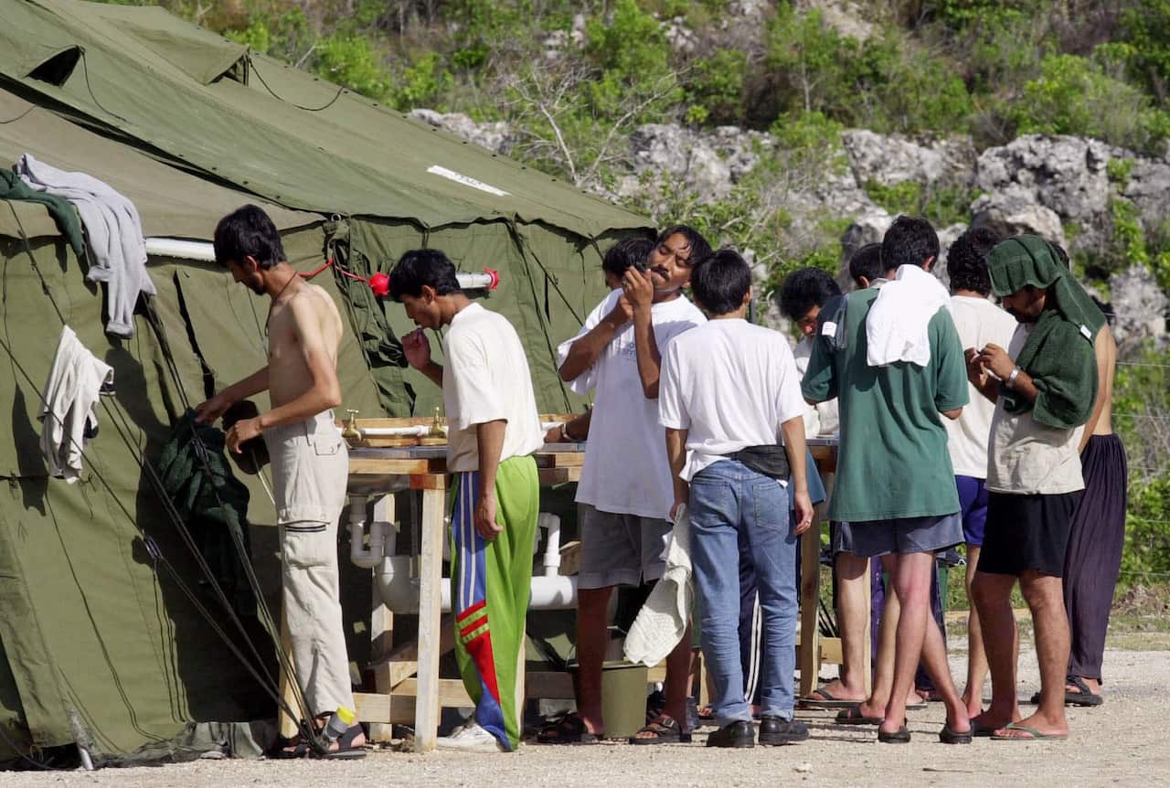 Men outside tents, shaving and brushing teeth at the start of the day at a refugee camp on the Island of Nauru. 