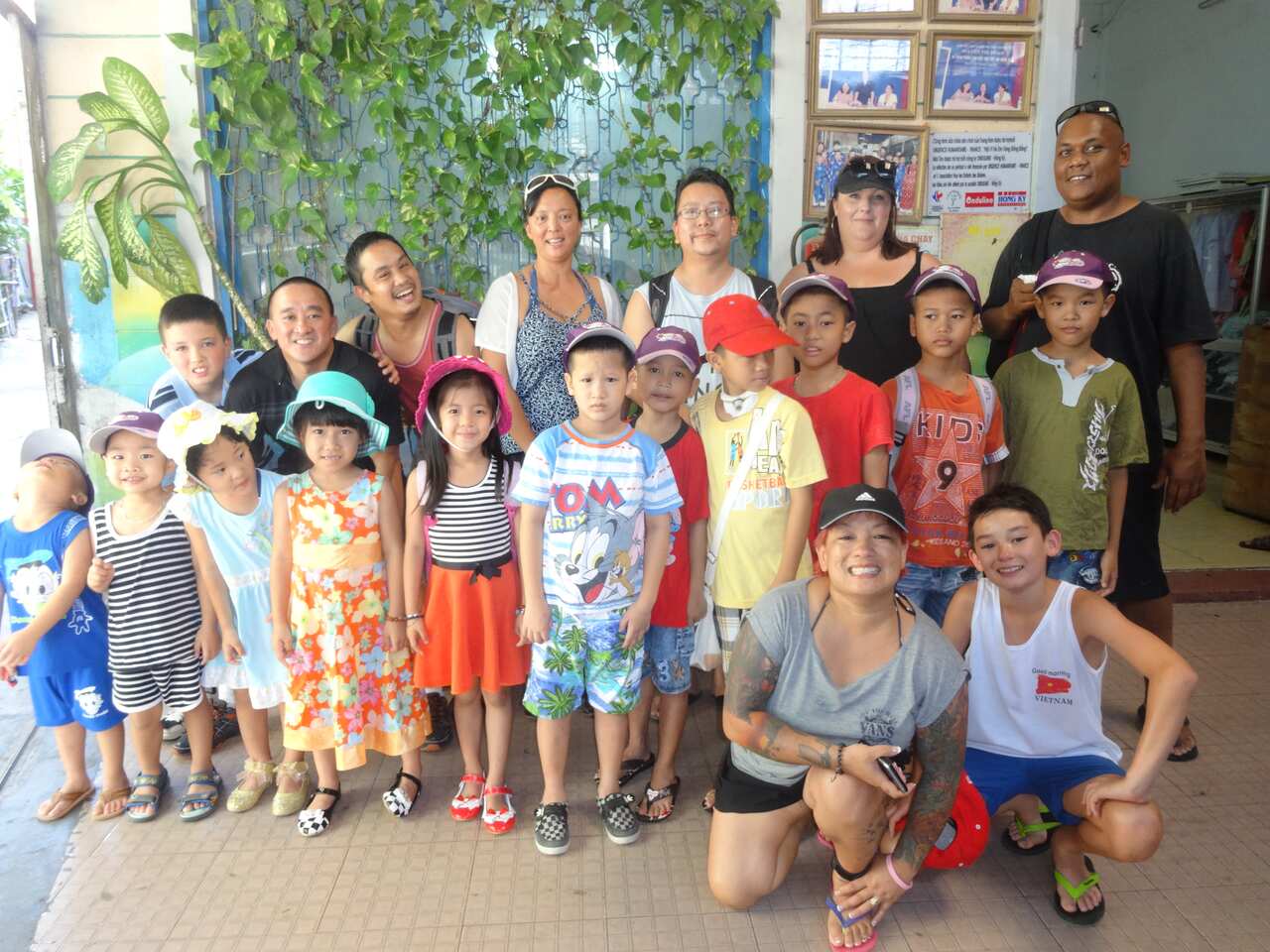 Several adult Vietnamese-Australian adoptees pose for a photo with Vietnamese children dressed in colourful clothes. 