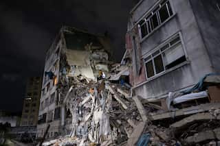 A concrete building has collapsed in the middle and is illuminated at night.