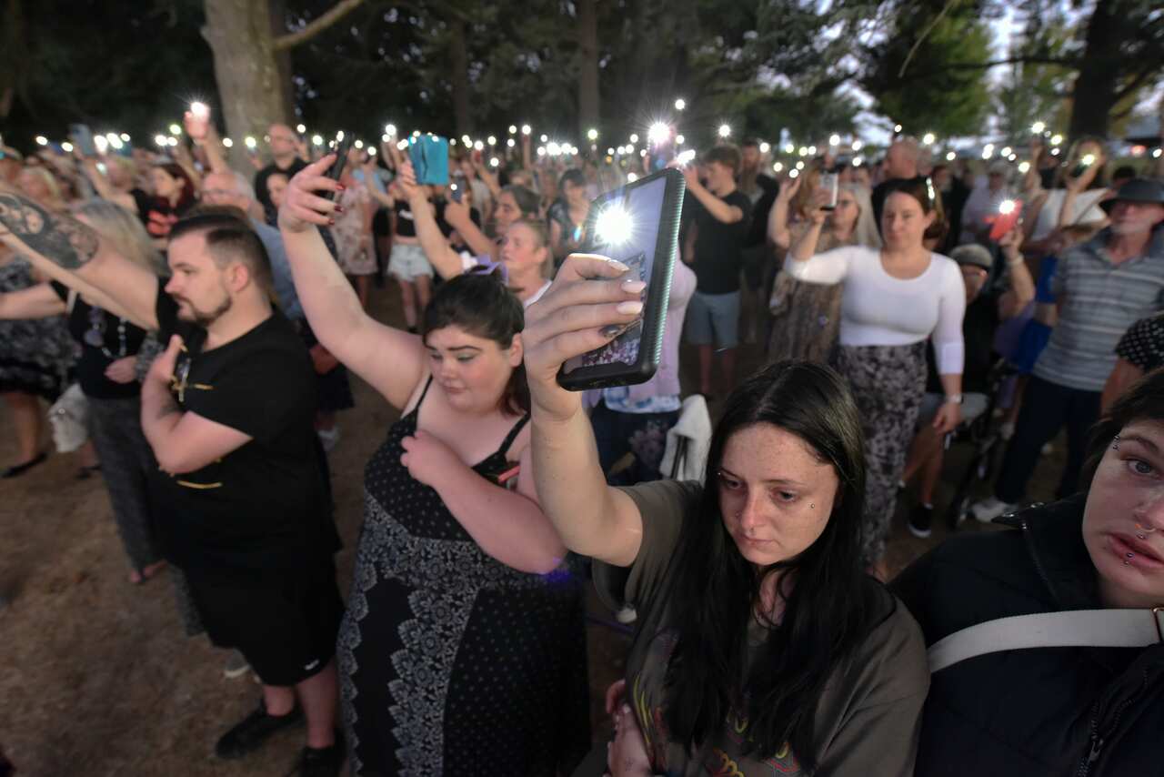 People hold up phones with the torches on