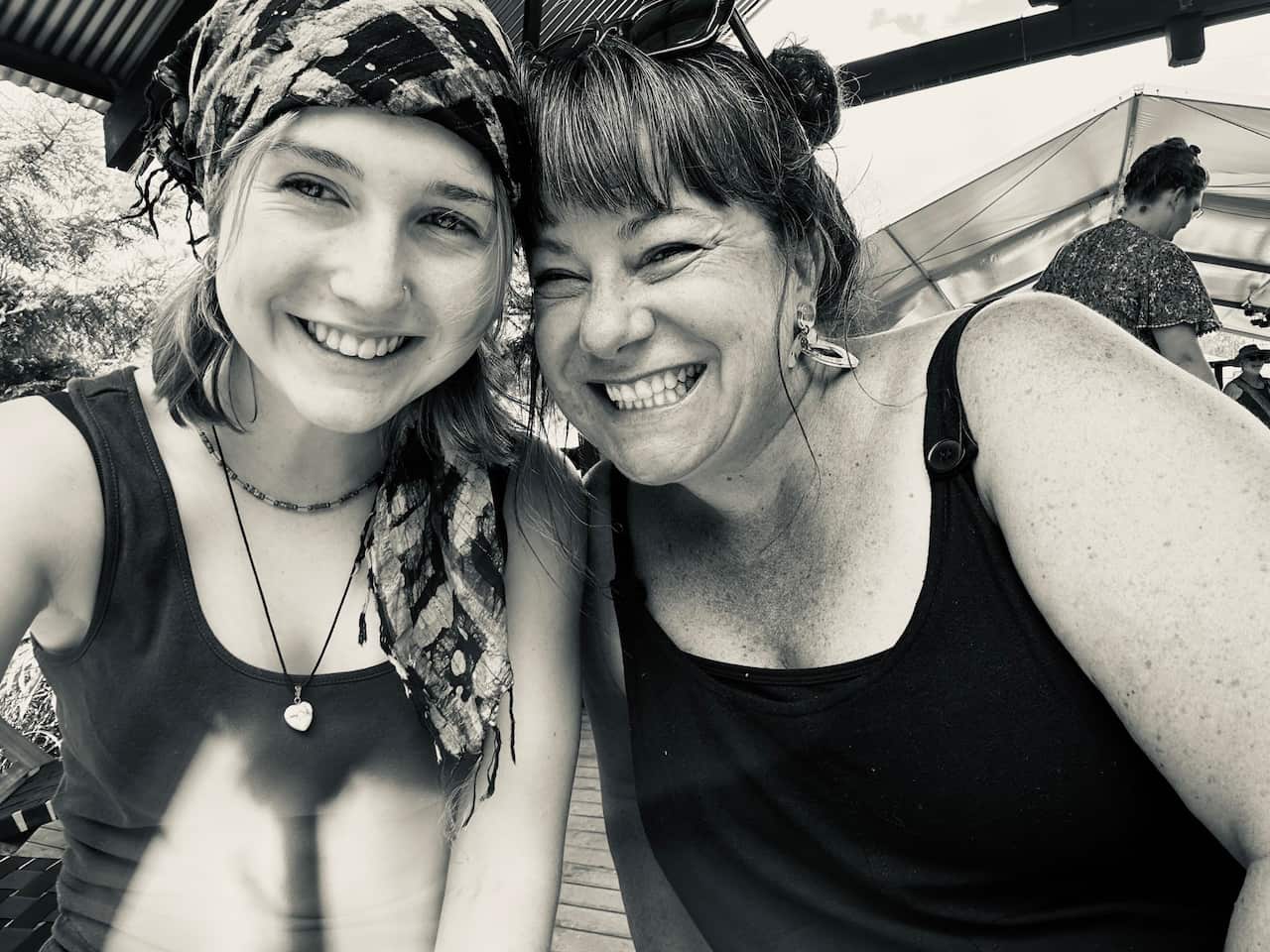 A black and white image of a girl wearing a scarf in her hair, posing with her mum