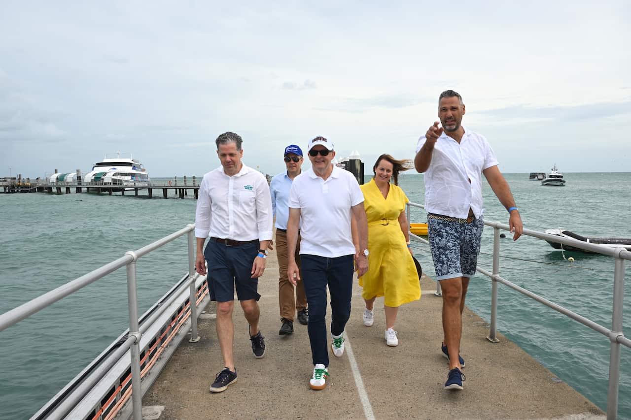 Anthony Albanese walks along a wharf flanked by Labor candidate and others. 