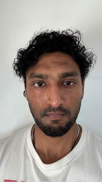 A headshot of a young man looking at the camera with a neutral expression on his face.