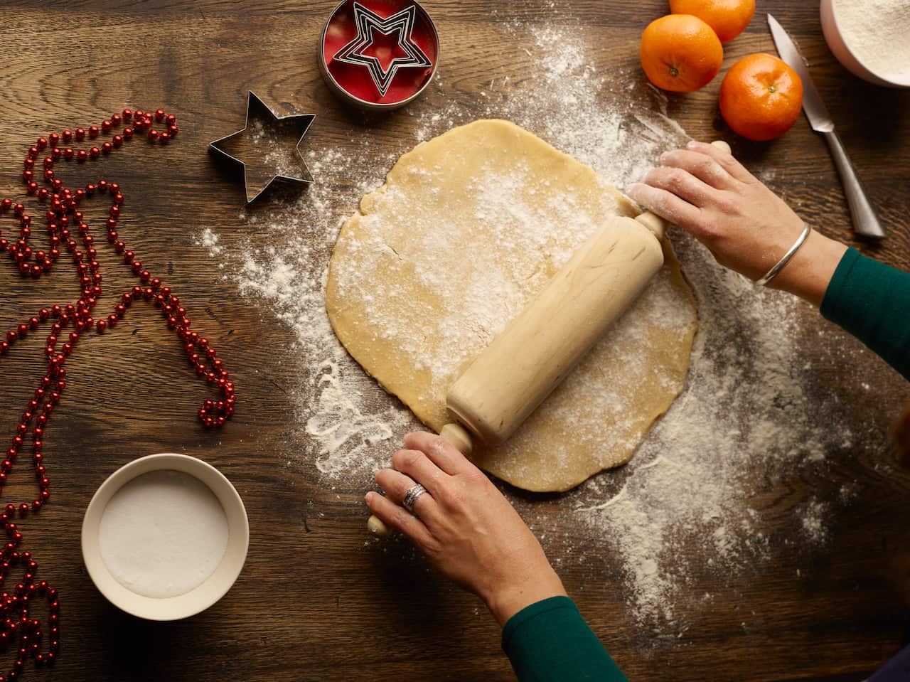 Overhead view of teenage girls hands rolling christmas star biscuit dough