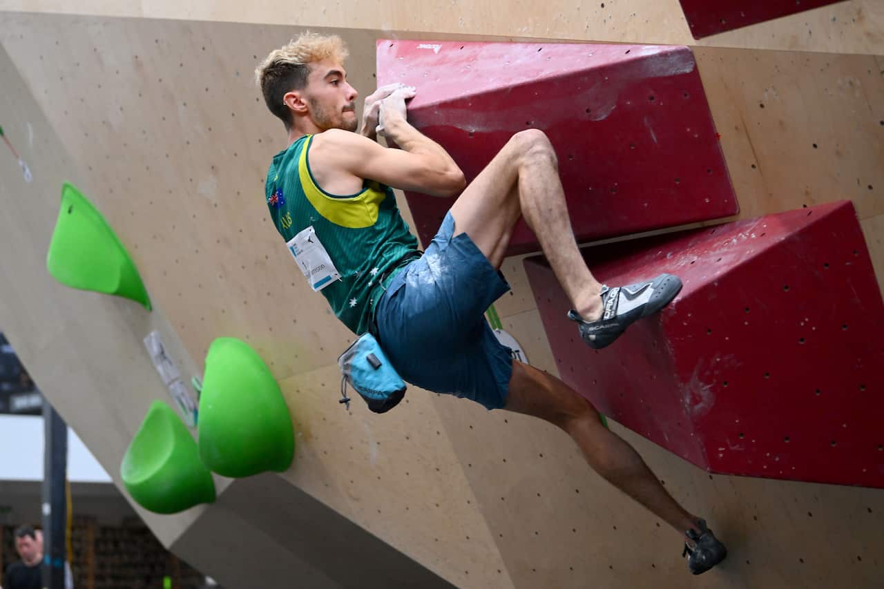 A man gripping a rock climbing wall.