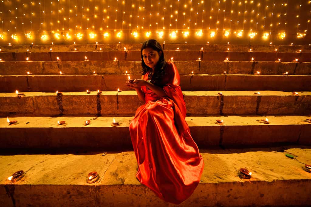 A lady poses for a photo while holding a Diya (Soil Made