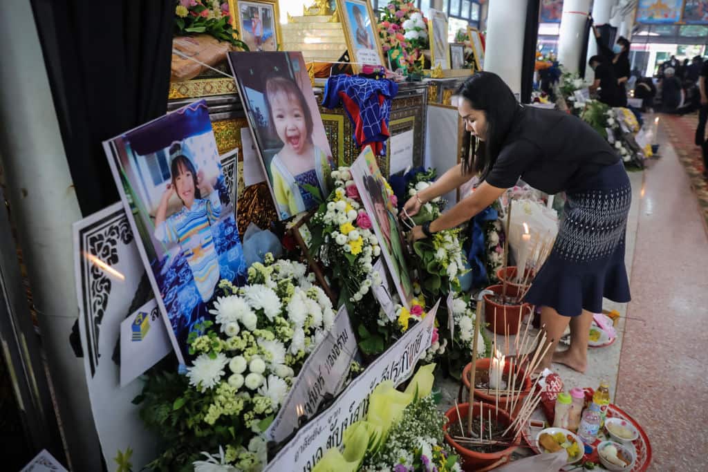 The relative of a victim places offerings and portraits at the Wat Rak Samakee temple before funeral rites take place on October 08, 2022 in Uthai Sawan subdistrict, Nong Bua Lamphu, Thailand.