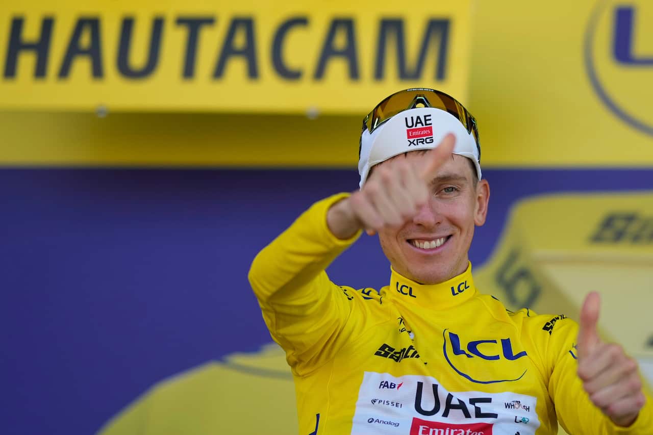 A man wearing a yellow cycling jersey smiles and gives a thumbs-up.