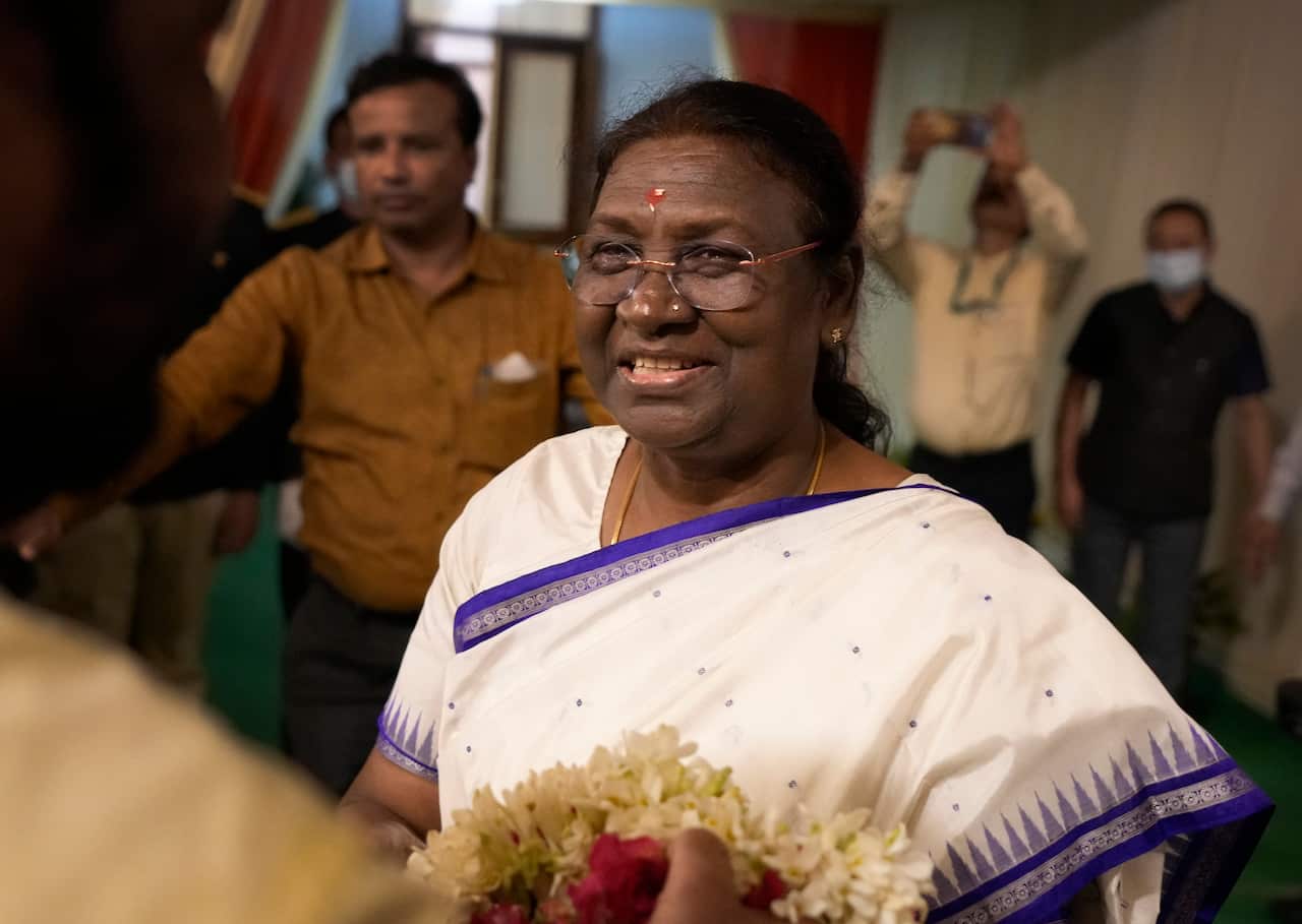 A woman in white traditional Indian dress, smiling.