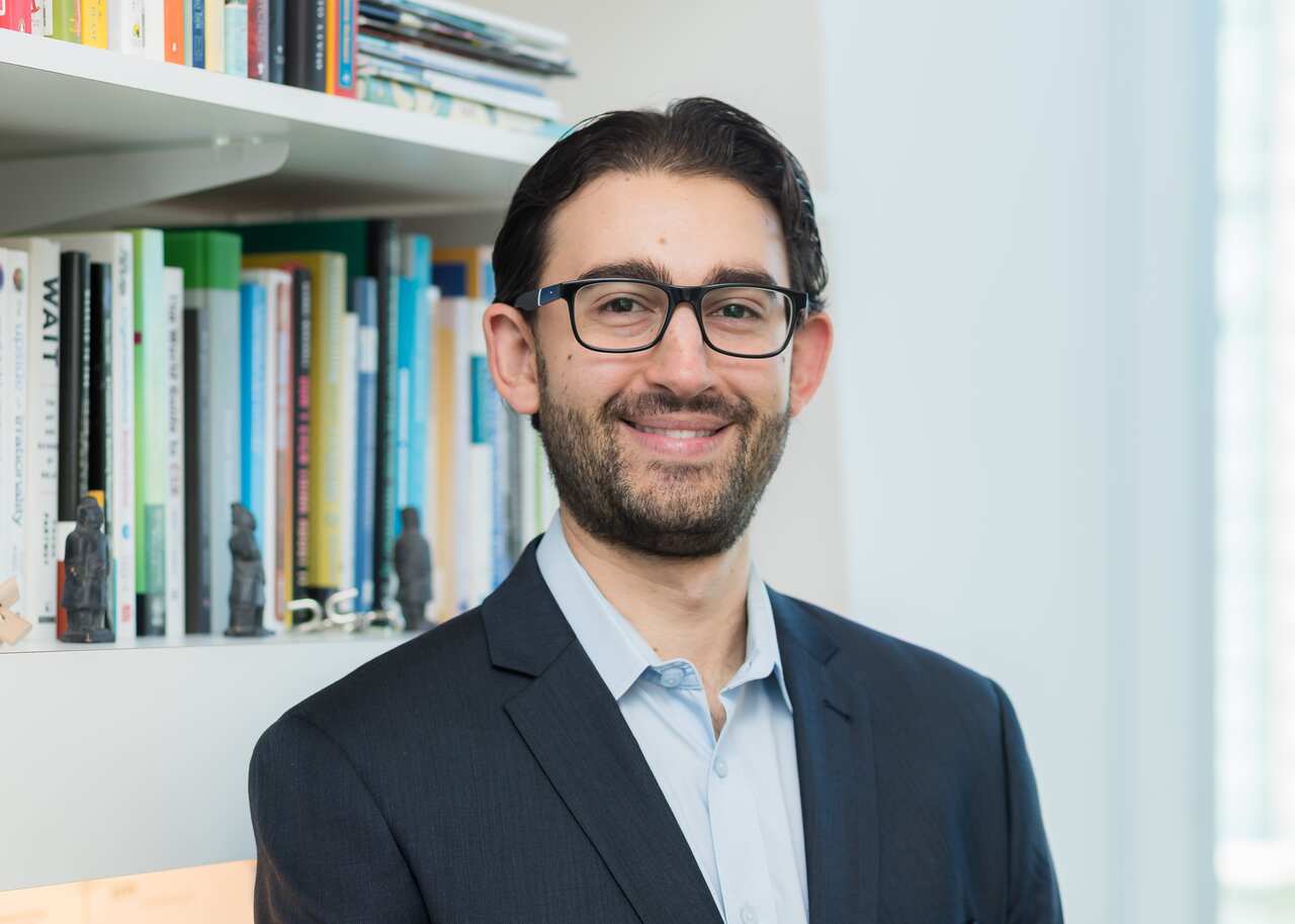 A man in a suit and glasses smiling