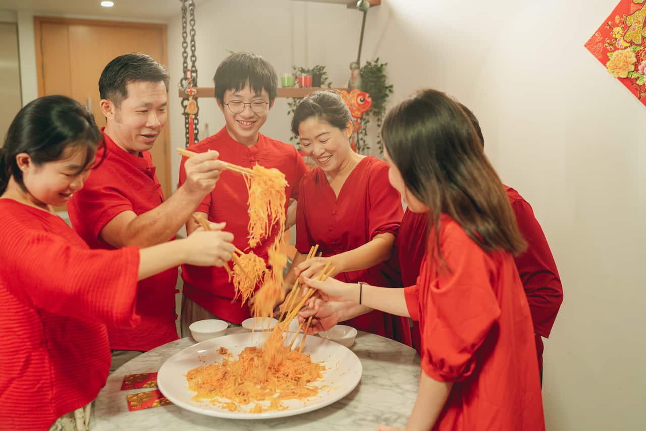 Multi generation family celebrates Chinese Traditional New Year with a prosperity toss or “Yee Sang”