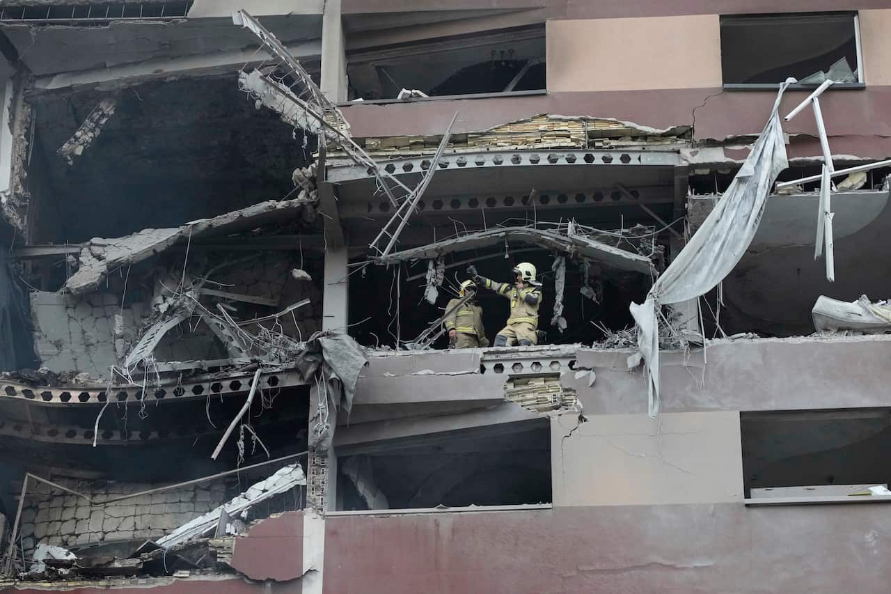 Firefighters working amid the rubble of a building which has been hit by a missile.